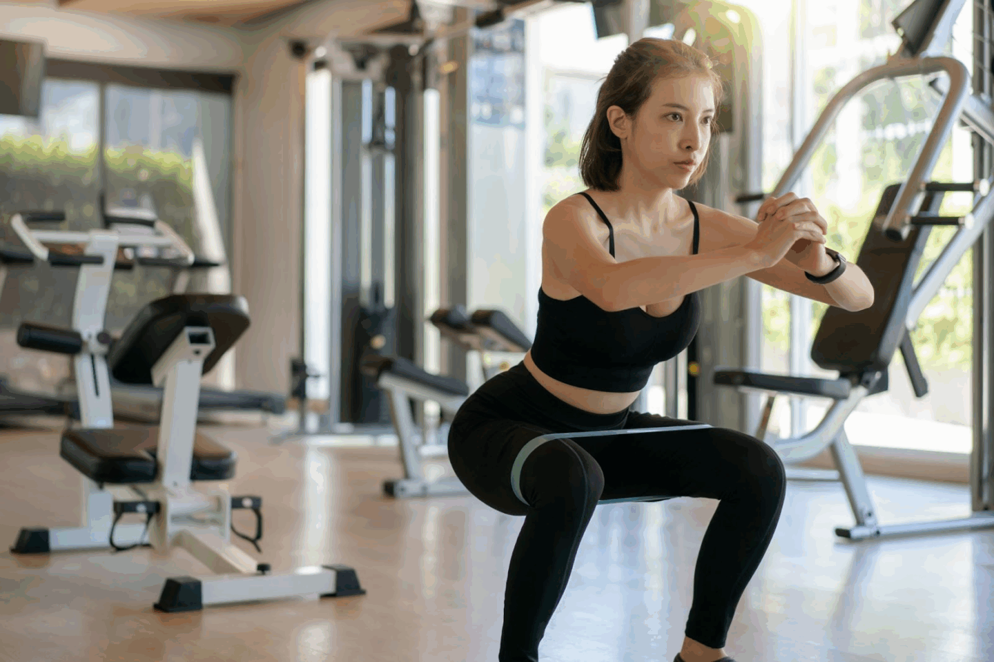 Woman doing squats in a gym setting.